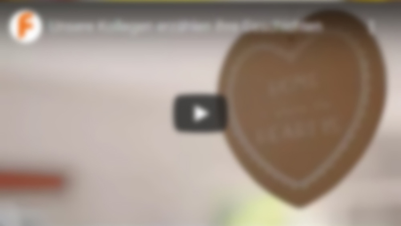 Video - Unsere Kollegen erzählen Ihre Geschichten mit Link zu Youtube Herzaufhänger im Vordergrund mit Aufschrift - Home Sweet Home